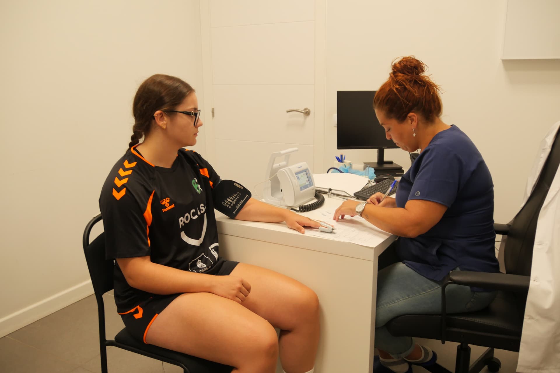 Profesional sanitaria tomando la tensión a una jugadora del Rocasa en consulta